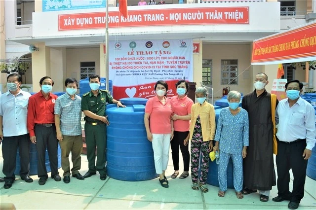 Bà Mai Thị Hạnh (áo hồng, khẩu trang xanh) trao bồn nước cho người dân ở huyện đảo Cù Lao Dung.