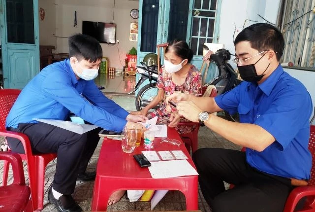 Cán bộ chuyên trách hỗ trợ làm thủ tục tại nhà cô Phạm Thị Hòa.