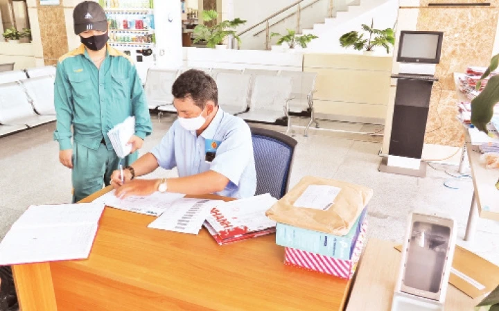 Cán bộ Văn phòng Cục Thuế TP Hồ Chí Minh tiếp nhận hồ sơ quyết toán thuế từ nhân viên bưu chính.