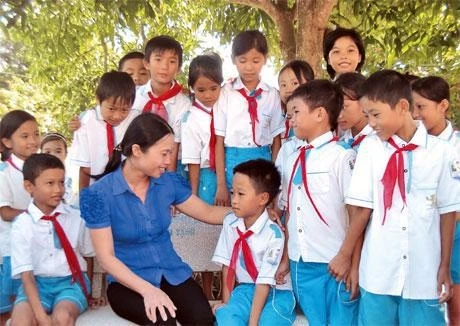 Bé Lê Văn Tuấn (nhiễm HIV) trong vòng tay yêu thương của cô giáo và bạn bè.